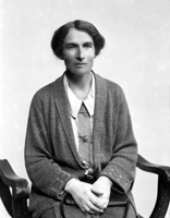 Woman seated wearing cardigan and gloves.#