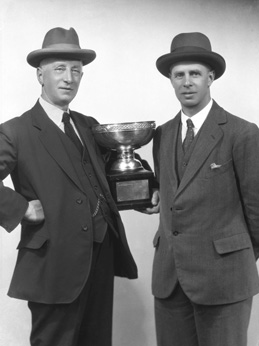 Two men holding a trophy. # 