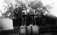 Series of images dating from September 1932 where the children are deep-etched from photographs and inserted into new illustrated backgrounds. The text on the rear of the original photo reads: 'See Viv's head popping up at the back! She's acting as a stone to prevent the drum from rolling.' #