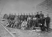 Gang of builders, including hard hat diver. Possibly bridge builders? Span of a bridge in background. (copy).*