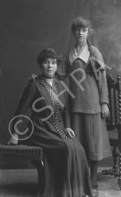 Elderly woman and young girl with long pleated ponytail, possibly mother and daughter.#