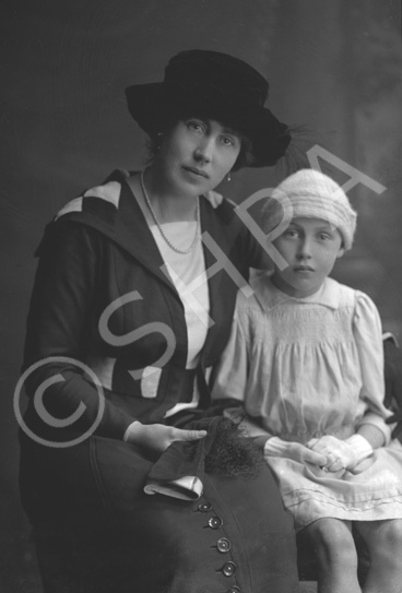 Mother seated with daughter.#