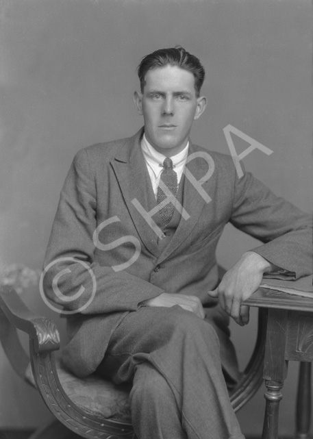 W. MacLean, seated with legs crossed.