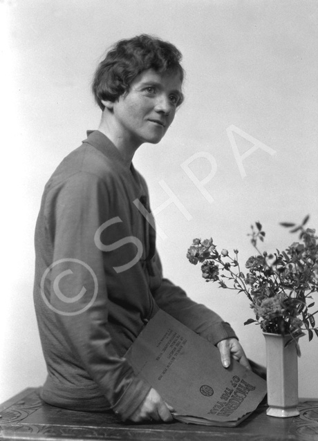 Female portrait. As a prop she is holding 'Photographs of the Year 1925,' the annual review for 1926 of the world's pictorial photographic work. #