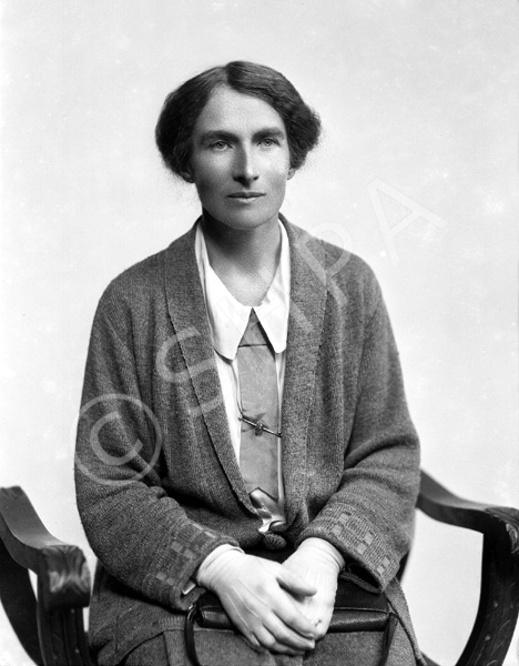 Woman seated wearing cardigan and gloves.#