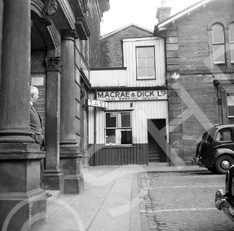 Macrae & Dick Taxi Booking Office in Station Square, the site now occupied by Mail Boxes Etc., with Ben Wyvis Kilts upstairs. The train station building is on the right.*
