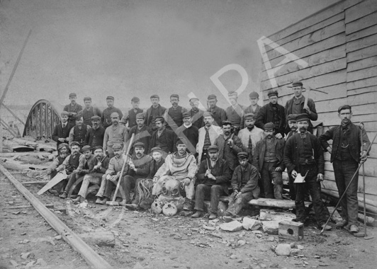 Gang of builders, including hard hat diver. Possibly bridge builders? Span of a bridge in background. (copy).*